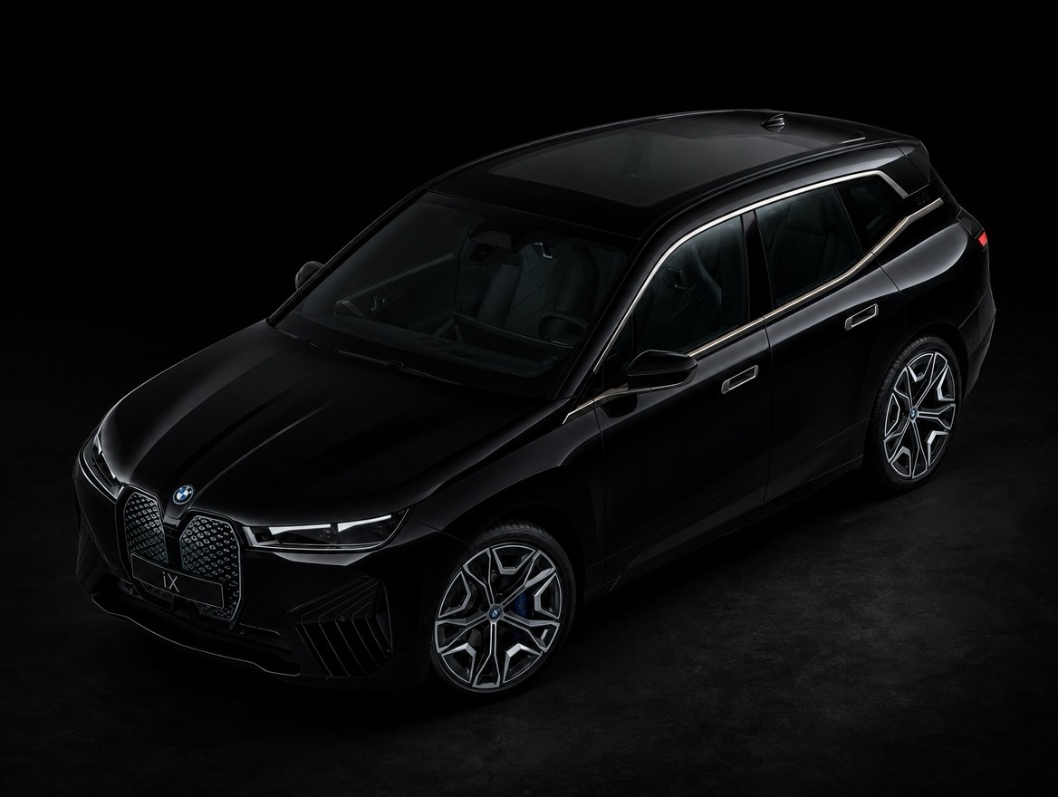 A black BMW iX from a high front three-quarter angle, the full length of its bodyside and roof in one frame