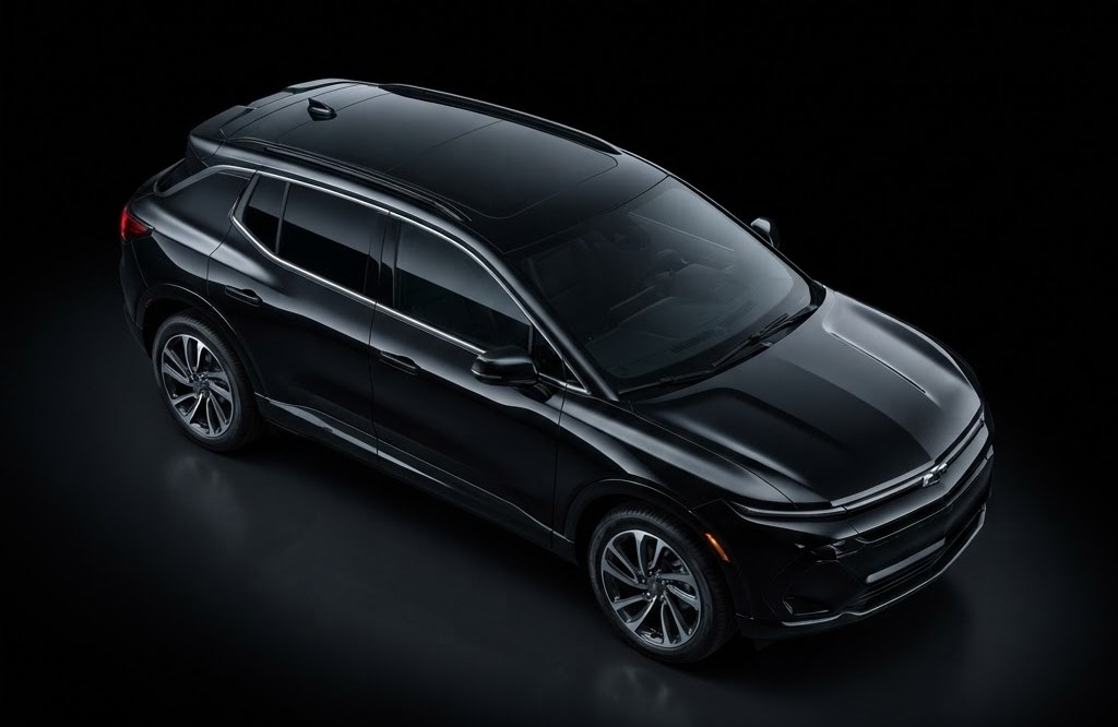 A black Chevrolet Equinox EV on a dark studio floor, seen from above and ahead of the front wing: the hood, the roof, the flank and the front wheel