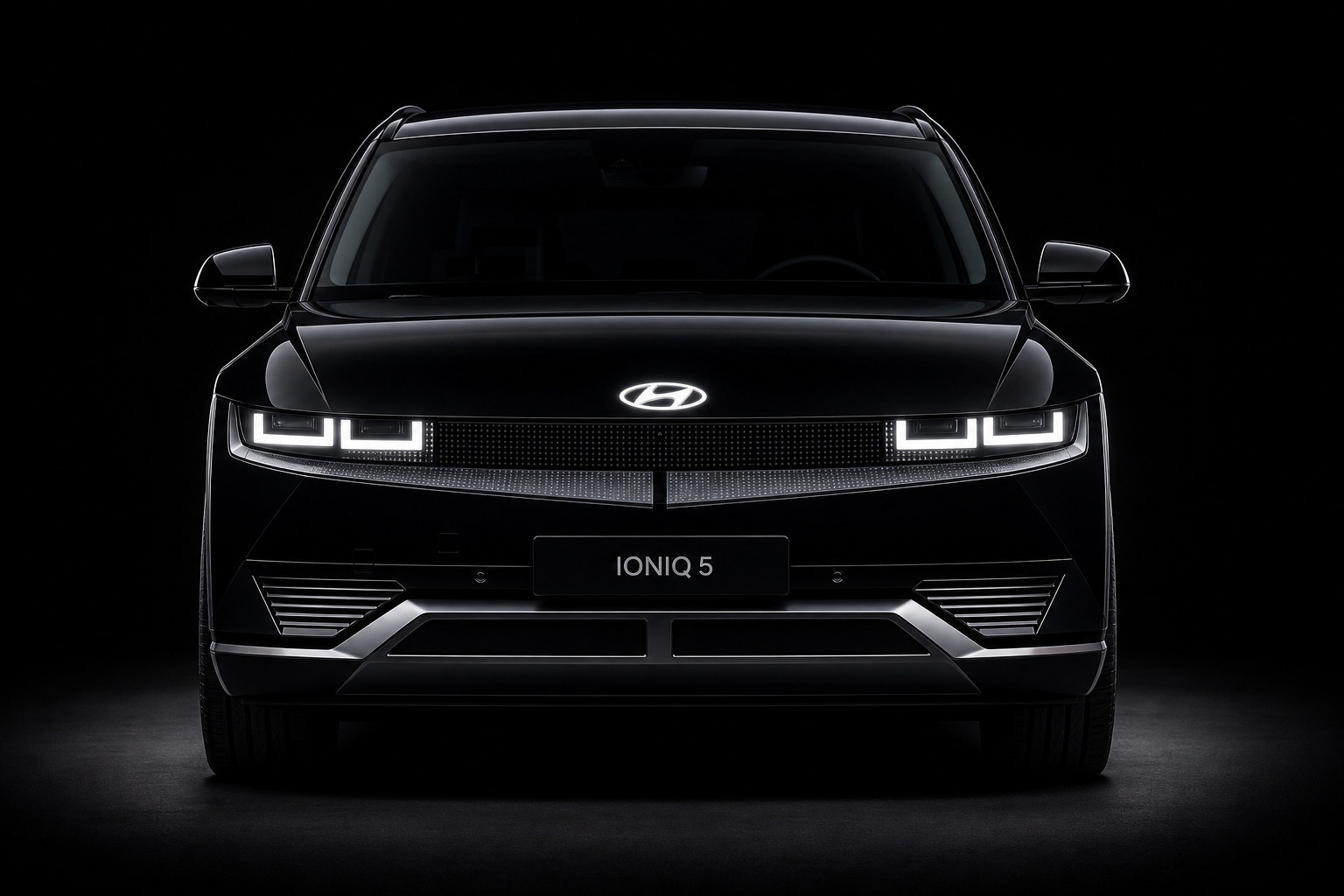 A black Hyundai Ioniq 5 head-on against a dark studio background: the pixel-lamp headlight clusters lit, the full-width light bar, the badge on the front lid and the lower bumper — the panels a collision repair replaces