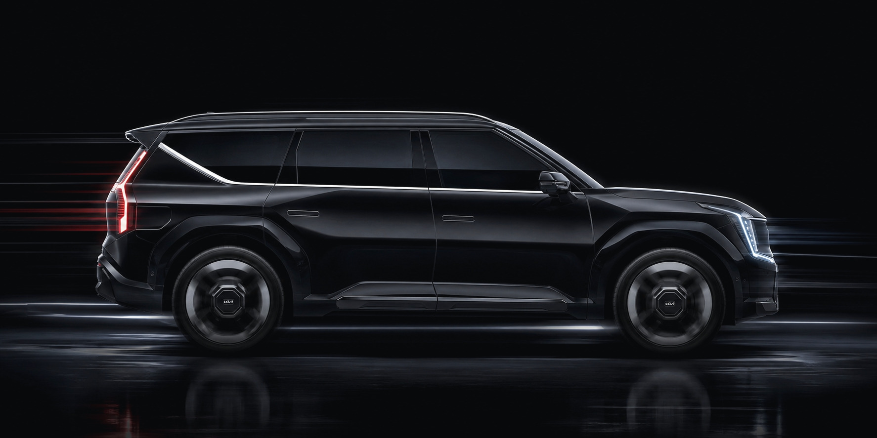 A black Kia EV9 in profile against a dark studio ground: the full flank, the rear lamp bar, the mirror housing and both bumpers — the panels a calibration has to be measured against