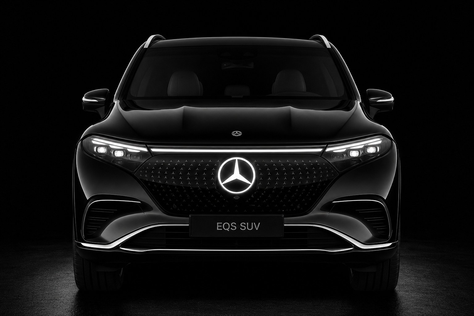 A black Mercedes-Benz EQS SUV head-on under studio light, the full front end in view: the star-pattern grille panel, the light bars across both ends of it and the EQS SUV placard on the bumper