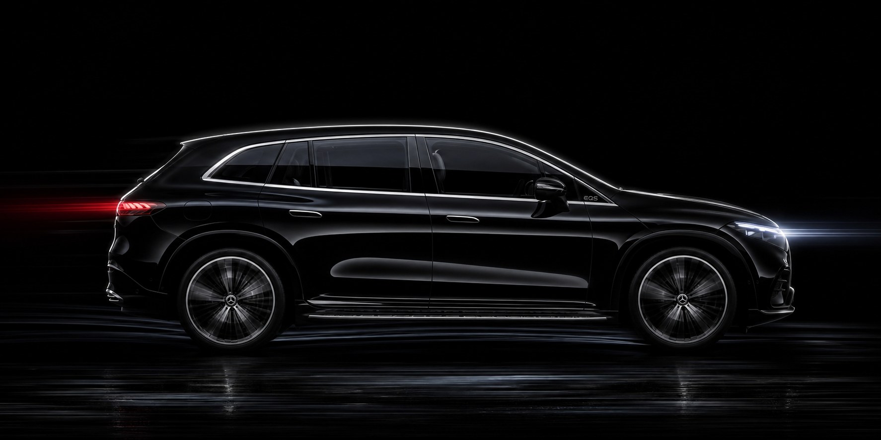 A black Mercedes-Benz EQS SUV in profile against a dark studio backdrop, the front bumper corners, mirrors and rocker line that carry the parking sensors and surround cameras in view