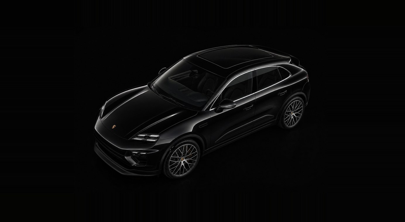 A black Porsche Macan Electric seen from above and ahead of the front wing against a dark studio backdrop