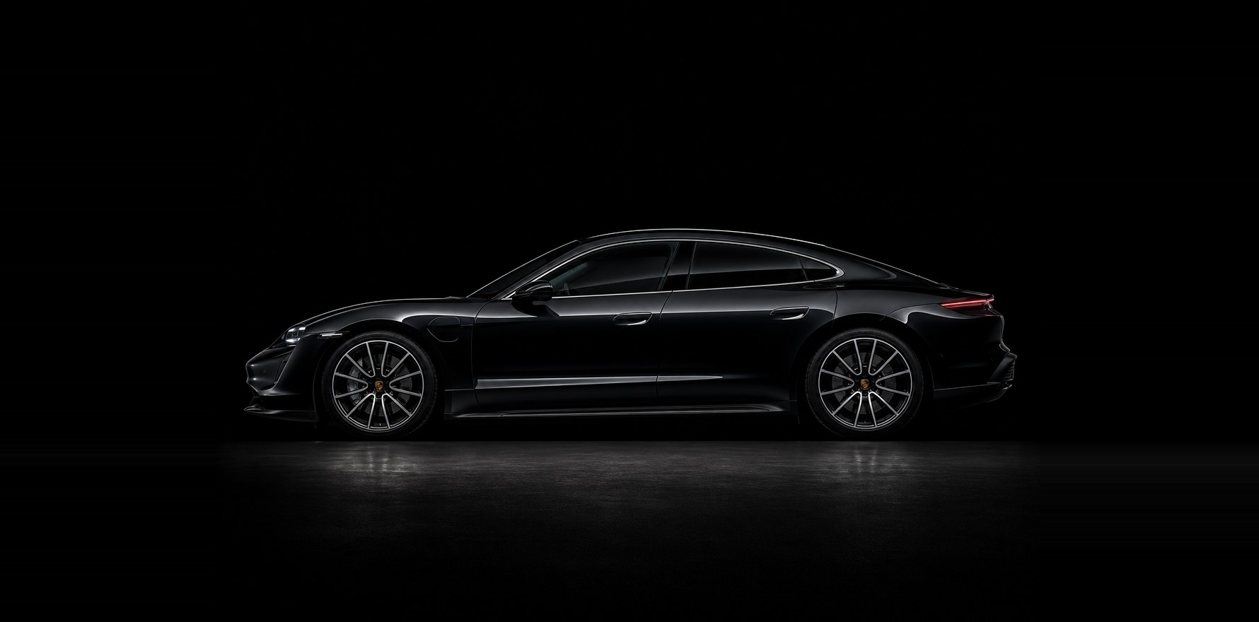 A black Porsche Taycan in profile under studio light, the full length of the body a calibration has to be measured against
